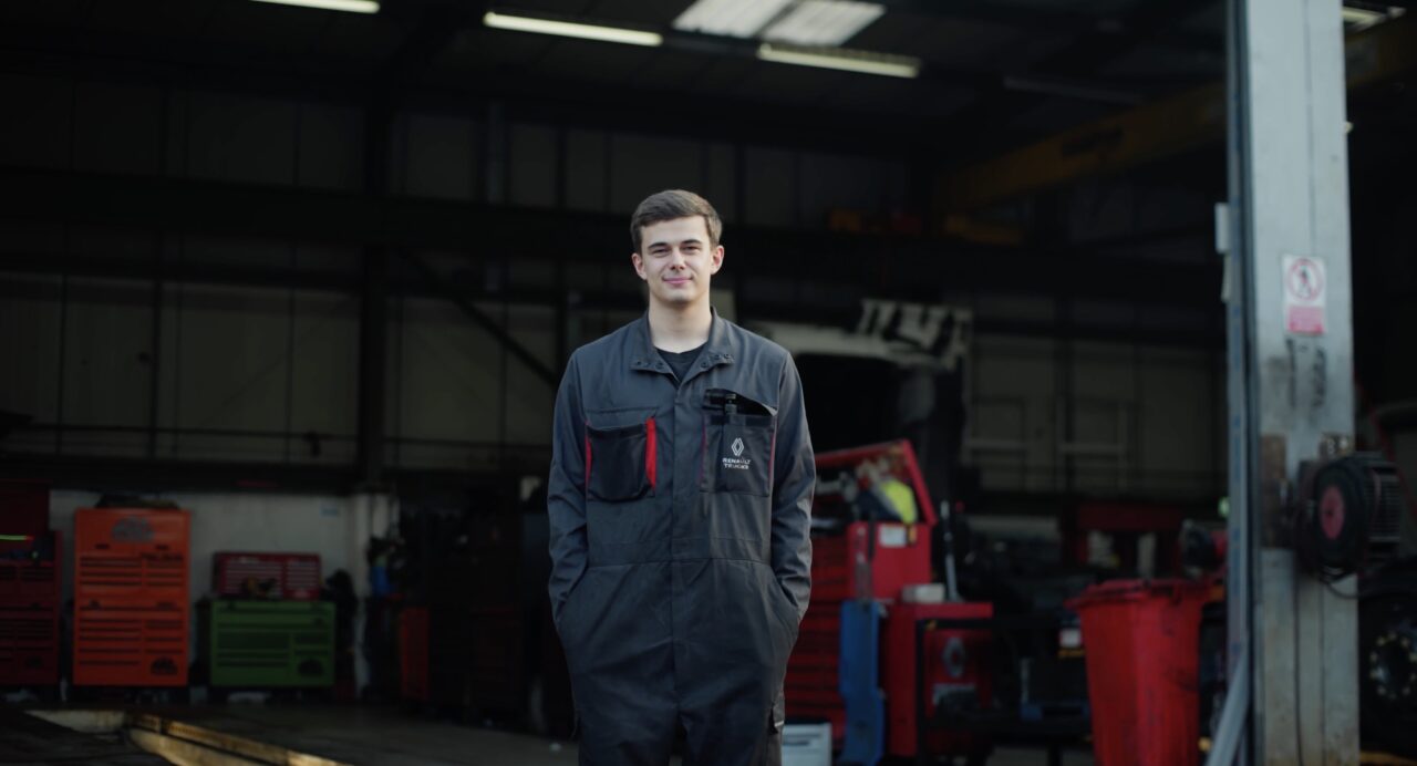 Technicien en uniforme de travail dans un atelier mécanique chez Renault Tucks avec des outils et des machines et des camions en arrière-plan pour le film de marque de son entreprise.